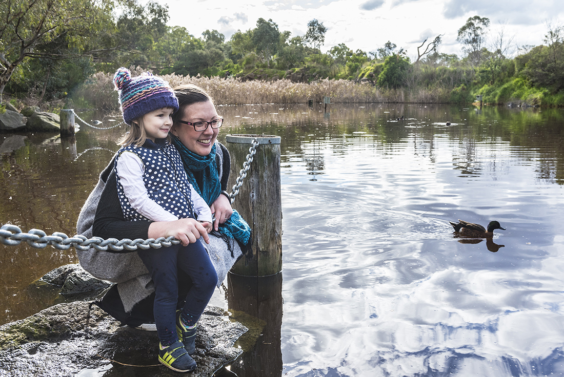 Mother and child looking at lake with ducks